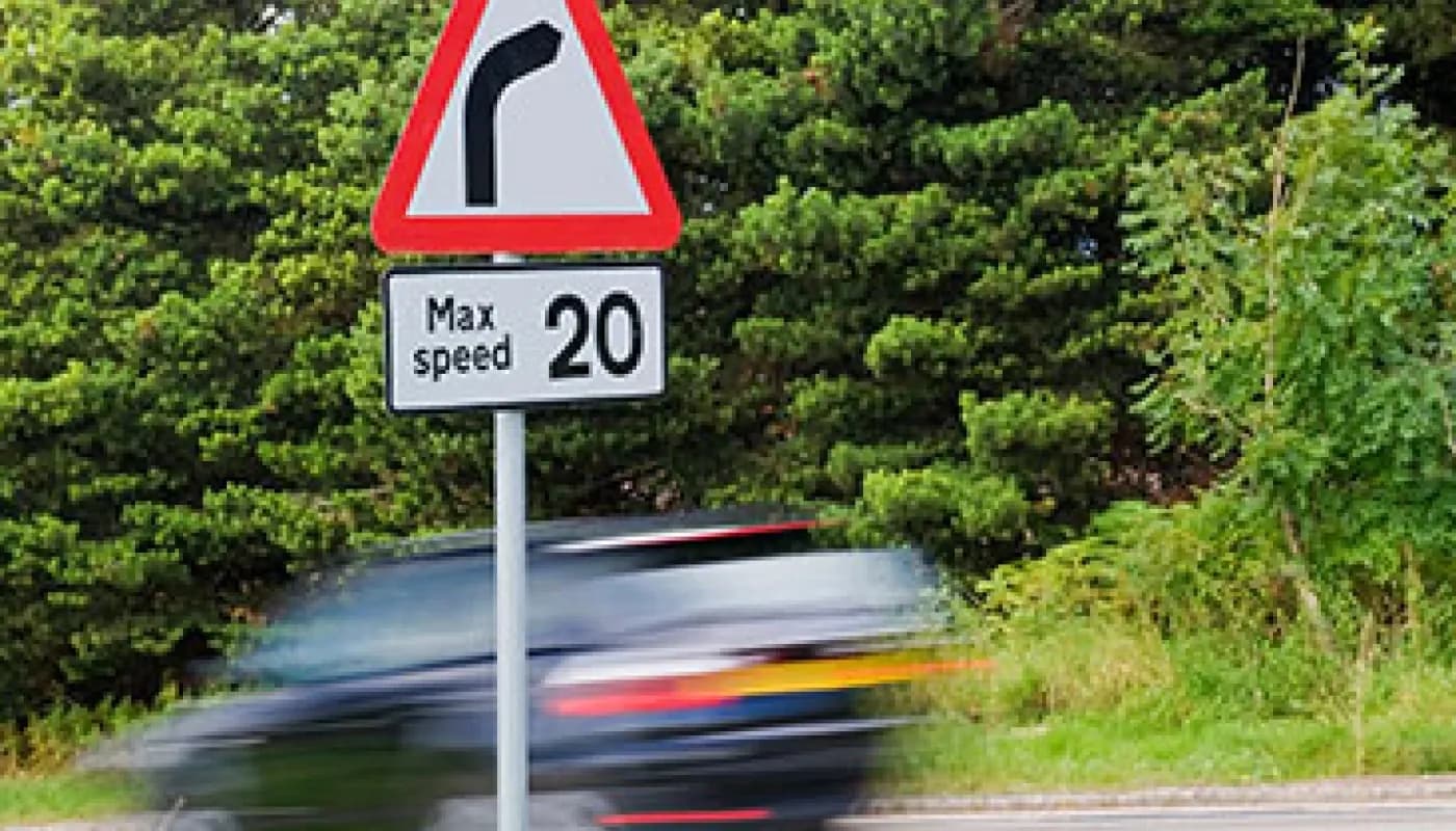 Car driving past a speed limit sign post