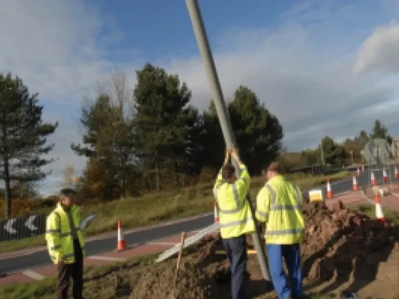 Road workers installing a frangible safety post